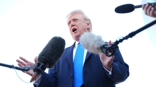 Trump speaking in front of microphones.