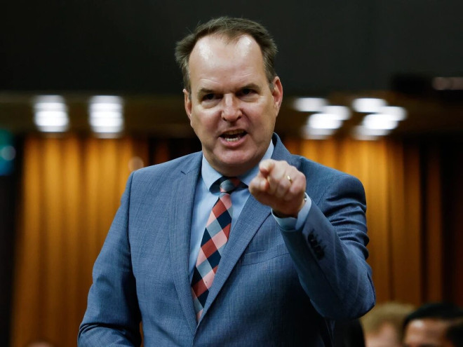 联邦运输部长 Steven MacKinnon 在众议院发言,指着前方。